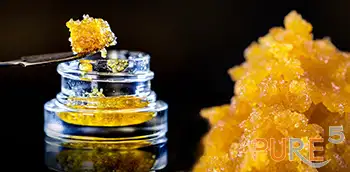 a jar with potent live resin with orange color on black background
