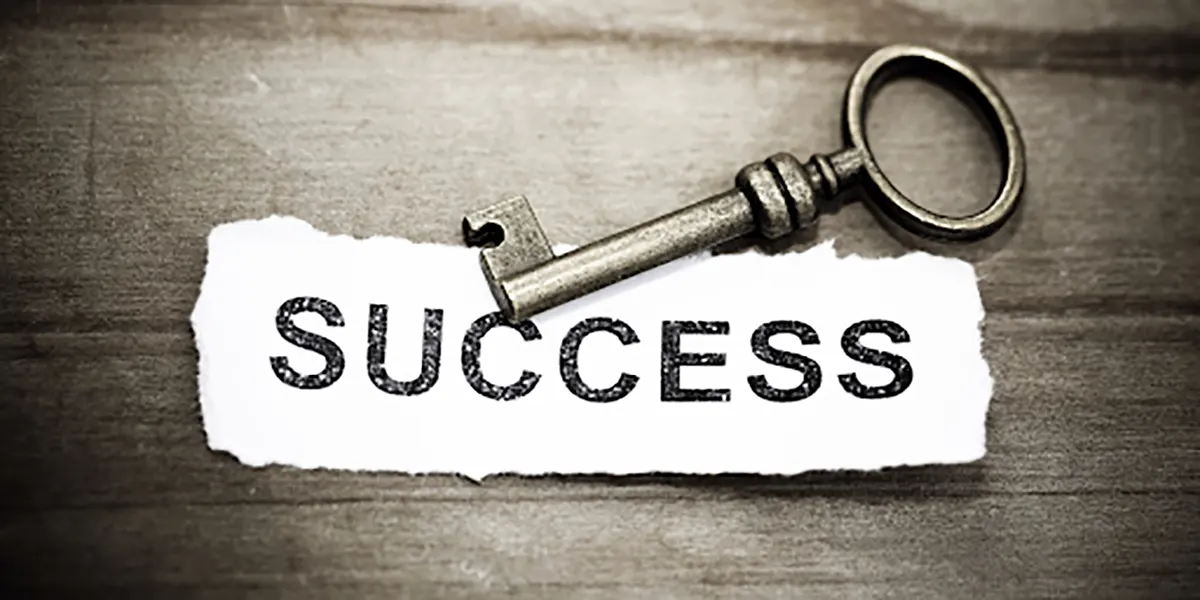 Success label and key on a wooden table.