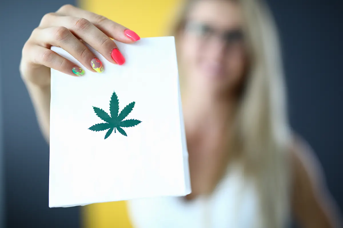 Cannabis leaf on a notebook and a woman on background